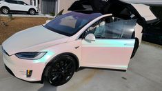 a white car parked in front of a house with its door open and the hood up