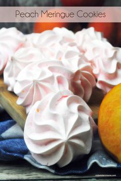 peach meringue cookies on a wooden table with fresh peaches in the background