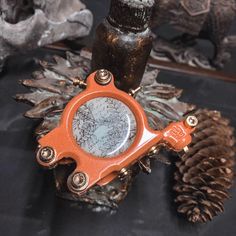 an orange magnifying glass sitting on top of a pine cone