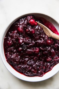 cranberry sauce in a white bowl with a wooden spoon