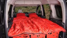 the back end of a van with an orange sleeping bag in it's cargo area