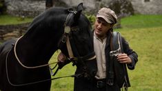 a man standing next to a black horse