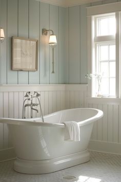 a white bath tub sitting in a bathroom next to a window with two lights on it