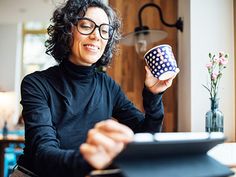 a woman sitting at a table with a cup in her hand