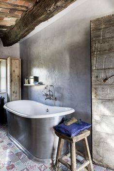 a bathroom with an old fashioned bathtub and stool in the corner, next to a wooden door