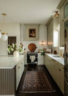 a kitchen with white cabinets and wooden floors, along with a rug on the floor