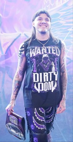 a man with long hair and tattoos wearing a black shirt holding a purple object in his hand