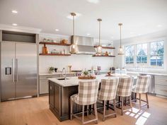 a kitchen with stainless steel appliances and checkered chairs in front of an island counter