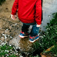 a little boy walking in the rain with his shoes on