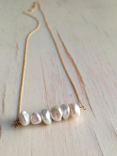 A delicate row of fresh water pearls is wire wrapped onto a 14k gold filled chain.Length is 17 inchesMATERIAL:GOLD-FILLED - 14k Gold filled is considerably durable and considered a lifetime piece of jewelry. This is NOT gold plated or gold dipped vermeil jewelry which can chip off over time with wear. Gold filled metal is essentially a 14k gold tube filled with an inner core metal such as brass and has been mechanically bonded with high very hot heat. It will never chip or flake off such as gold Pearl Bar Necklace, Pearl Birthstone, Fine Silver Jewelry, Gold Bar Necklace, June Birthstone, Bijoux Diy, Love Necklace, Gold Filled Jewelry, Elegant Jewelry