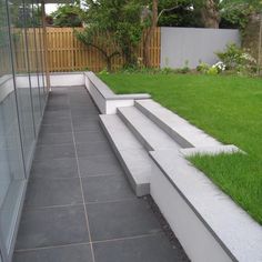 some concrete steps in front of a fence and green grass on the side of a building