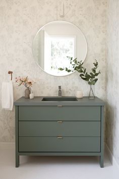 Minimalist Evergreen Fog vanity with flat-front design, solid white countertop, and round mirror in a fresh setting. Evergreen Fog Vanity, Delicate Wallpaper