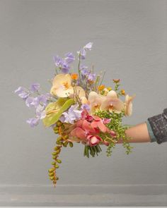 a person holding a bouquet of flowers in their left hand and the other hand is touching it