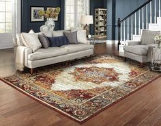 a living room filled with furniture and a rug on top of a hard wood floor