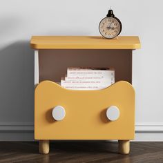 an alarm clock sitting on top of a yellow shelf next to a book and magazines