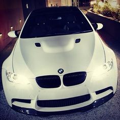 a white car parked in front of a building with lights on it's hood