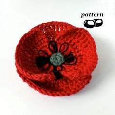 a crocheted red hat with a black bow on it and a button in the center