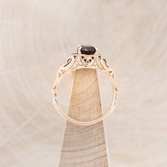 a gold ring with a black diamond sits on top of a wooden stand