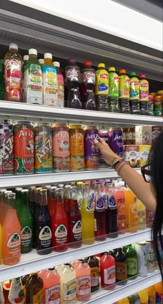 a woman is taking a photo in front of a display of juices and drinks