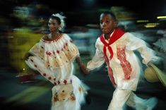 two people dressed in white and red are walking down the street with their arms around each other