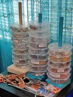 there are many plastic containers on the table with beads and other items in front of them