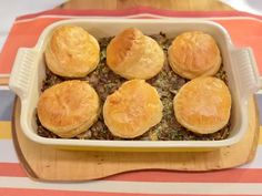 a casserole dish filled with baked goods on top of a wooden cutting board