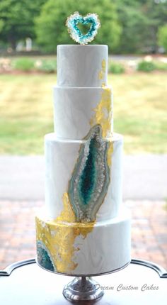 a three tiered white cake with gold and blue designs on it's sides