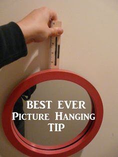 a person holding a measuring tape in front of a mirror with the words best ever picture hanging tip