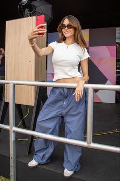 a woman taking a selfie with her cell phone while standing in front of a camera