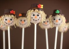 cake pops with frosting decorated as scarecrows and hats on them, sitting in front of a brown background