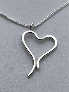 This pendant is made from a piece of  sterling silver wire. This is an unusual  fabricated piece which has been designed and made using traditional handmade techniques. It is an open heart with a free form. This Sterling Silver Pendant comes with a 18 inch Curb Chain. There are TWO options for this pendant the larger one is made from a piece of 1.8mm Sterling Silver wire whilst the smaller one is made from 1.5mm wire. Each are delivered in a Leather and velvet box for ideal presentation. Sterling Silver Heart Necklace Wire Wrapped, Silver Heart Necklace, Hand Forged, Silver Hand Forged Heart Necklace, Hand Forged Silver Heart Necklace, Sterling Silver Open Heart Necklace, Hand Forged Silver Heart Jewelry, Nickel-free Sterling Silver Open Heart Necklace, Nickel-free Open Heart Sterling Silver Necklace, Minimalist Handmade Open Heart Jewelry