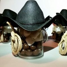 there is a glass jar with chocolate candies in it and two cowboy hats on top