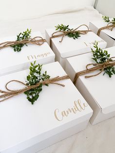 four white boxes tied with twine and greenery