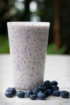 a glass filled with blueberries sitting on top of a table