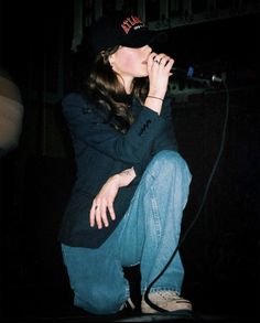 a woman sitting on the ground singing into a microphone