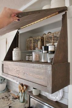 a person is holding a piece of wood above a stove top shelf in a kitchen