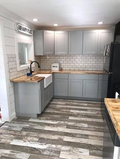 a kitchen with gray cabinets and wood flooring