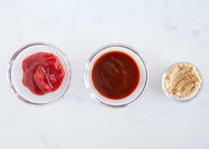 three bowls filled with different types of sauces and seasonings on a white surface