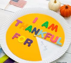 a paper plate with the words i am grateful for written on it next to markers and pumpkins