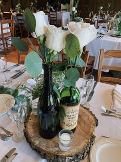 the table is set with wine bottles and flowers in vases on top of a tree stump