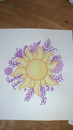 a drawing of a sun surrounded by purple and yellow flowers on white paper with crayons next to it