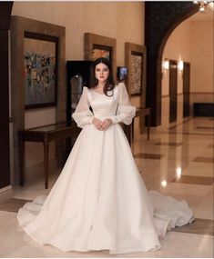 a woman in a white wedding dress standing on the floor