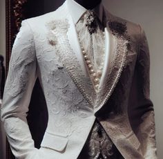 a mannequin dressed in a white tuxedo with pearls on the lapel