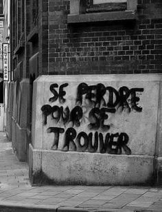 black and white photograph of graffiti writing on the side of a building in an alleyway