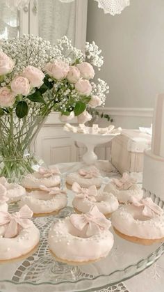 a glass plate topped with donuts covered in frosting next to a vase filled with flowers