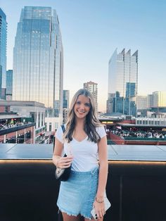 a woman standing on top of a roof with her hand in her pocket and looking at the camera