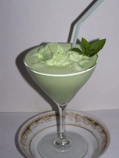 a green drink with ice cream and mint garnish in a glass on a plate