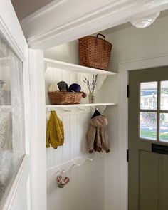 an entry way with white shelves and baskets on the top shelf, next to a door