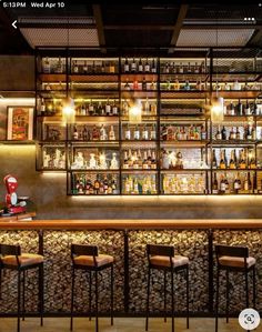 an image of a bar with lots of bottles on the wall and stools in front of it