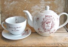 a tea pot and saucer sitting next to each other on a wooden table top